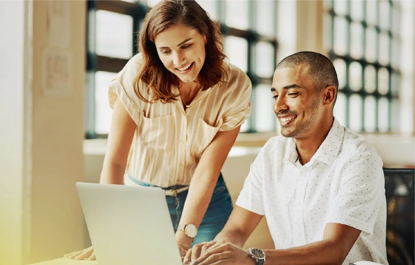 Homem e mulher sorrindo visualizando vagas da BeOps em um laptop